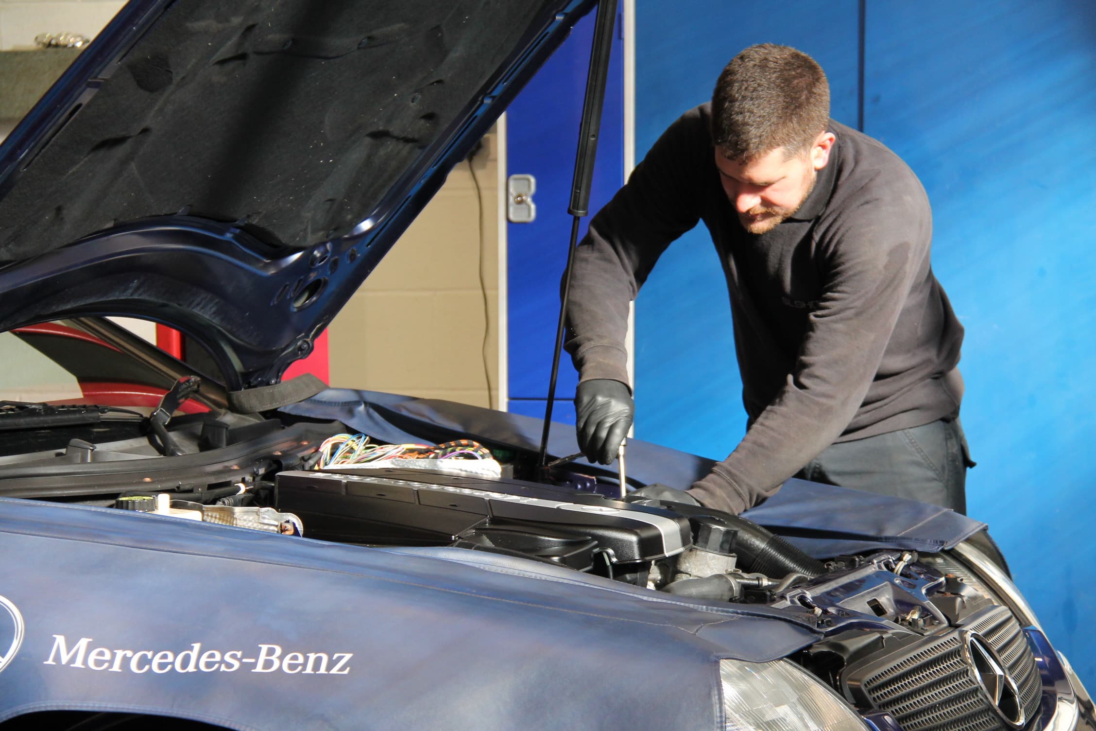 Mechanic removing engine cover on a R129 SL.