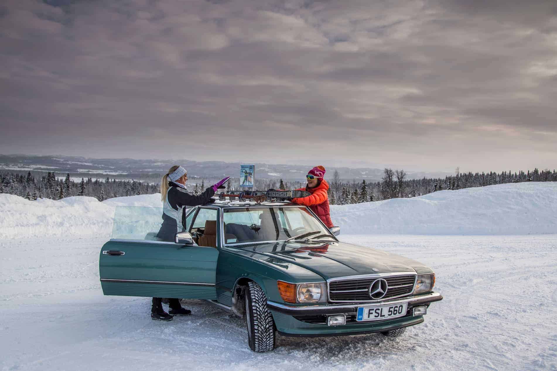Two skiers fixing their skis to our 1980s 560SL Mercedes