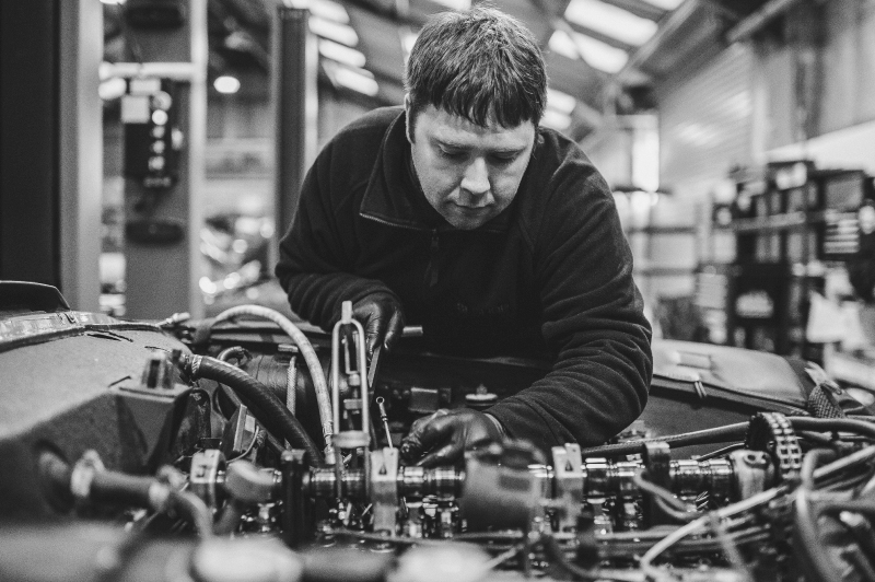 Man examining car engine during W113 Servicing. 