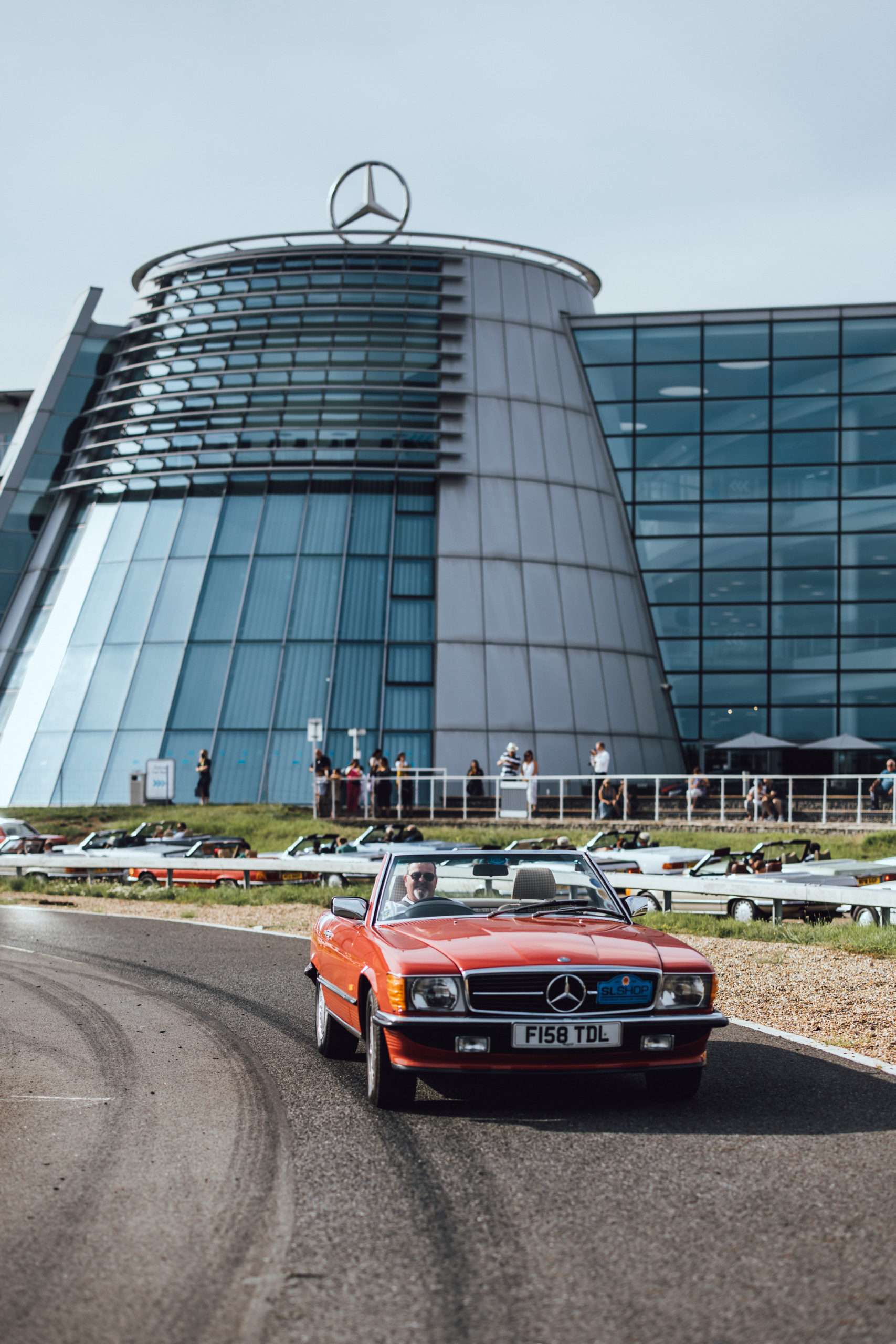 Signal Red R107 SL driving past Mercedes-Benz World