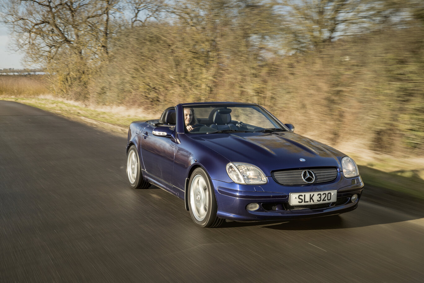 Mercedes SLK driving down a country road.