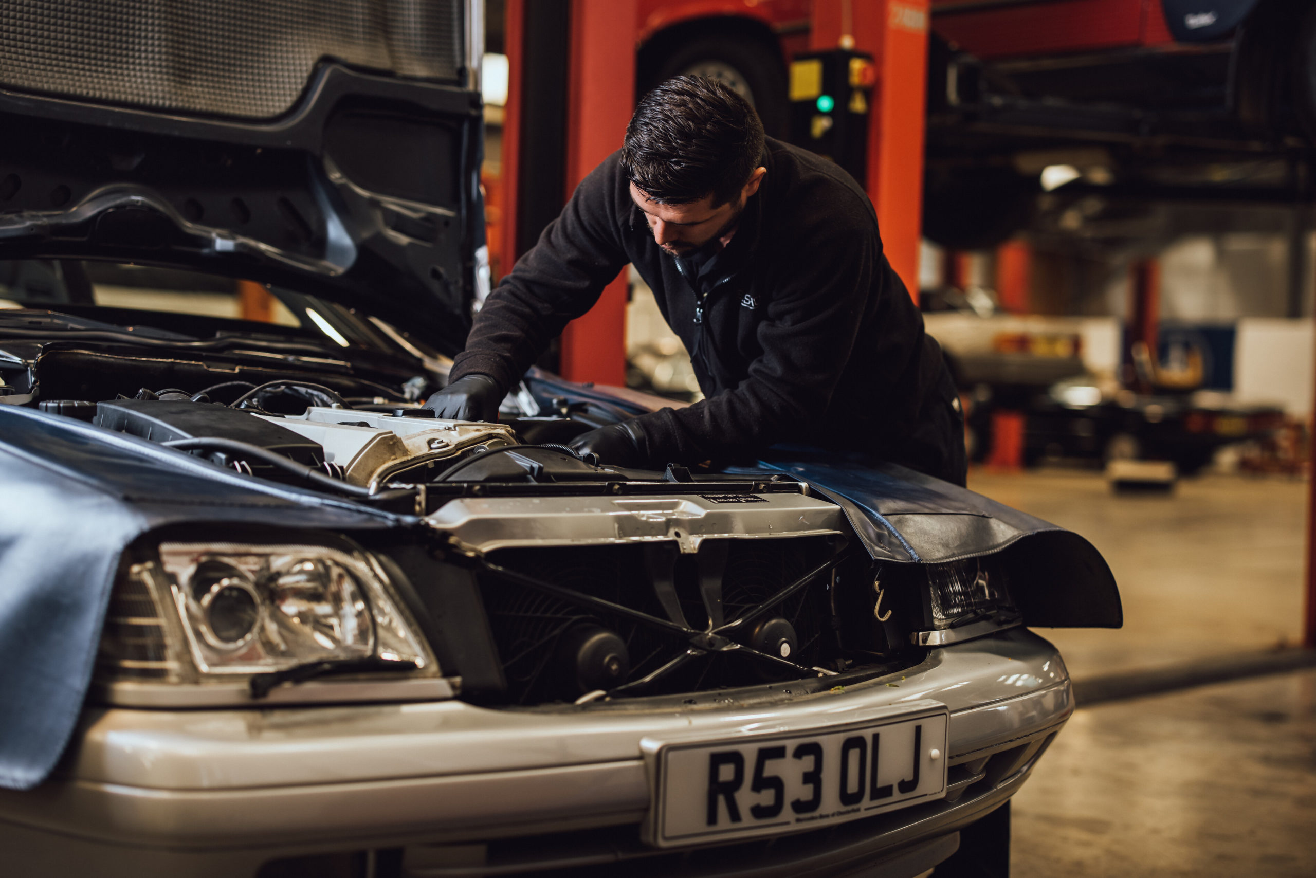 Mechanic inspecting an R129 SL's engine