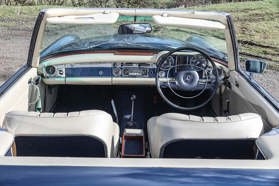Interior shot of 280SL Pagoda with natural leather, body matched dash and carpets, and black steering wheel. 