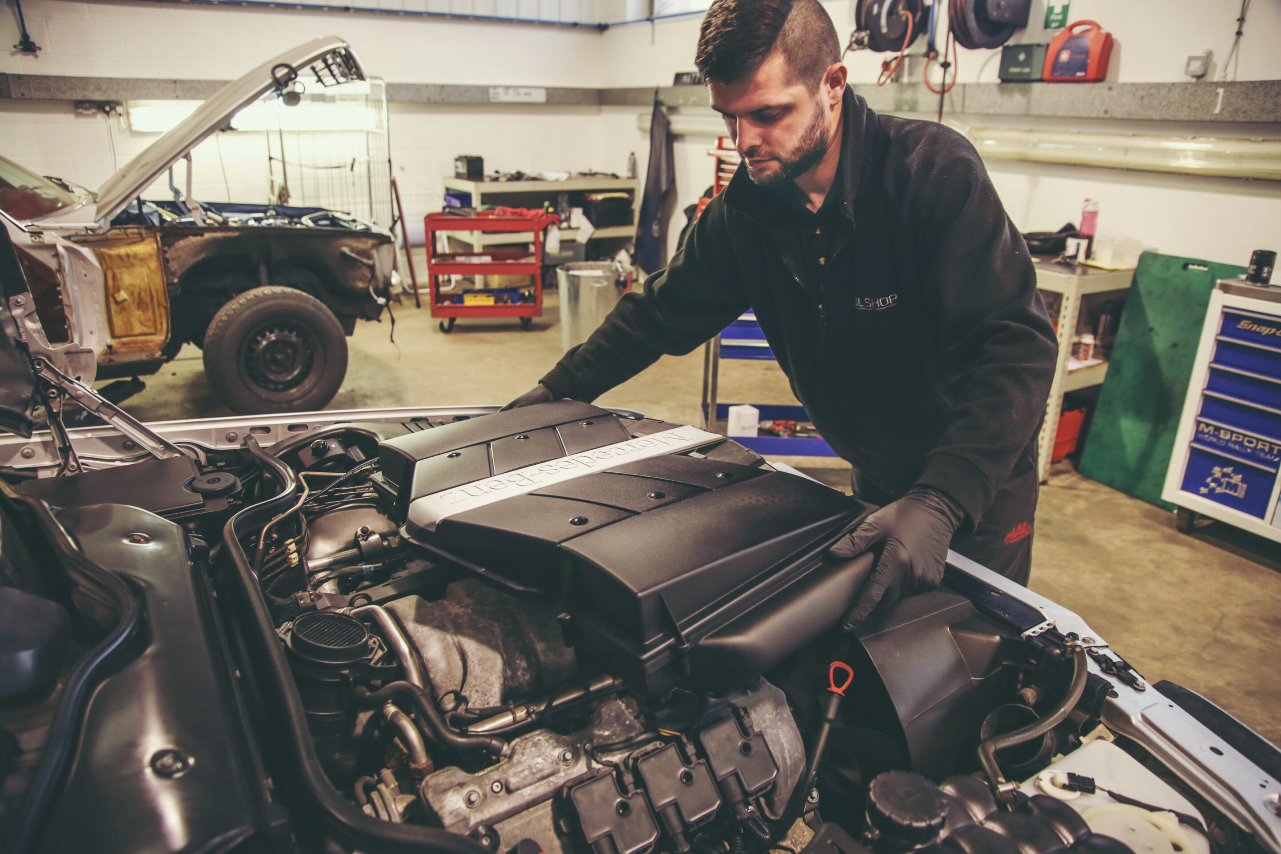 Mechanic removing engine cover on a R129 SL.