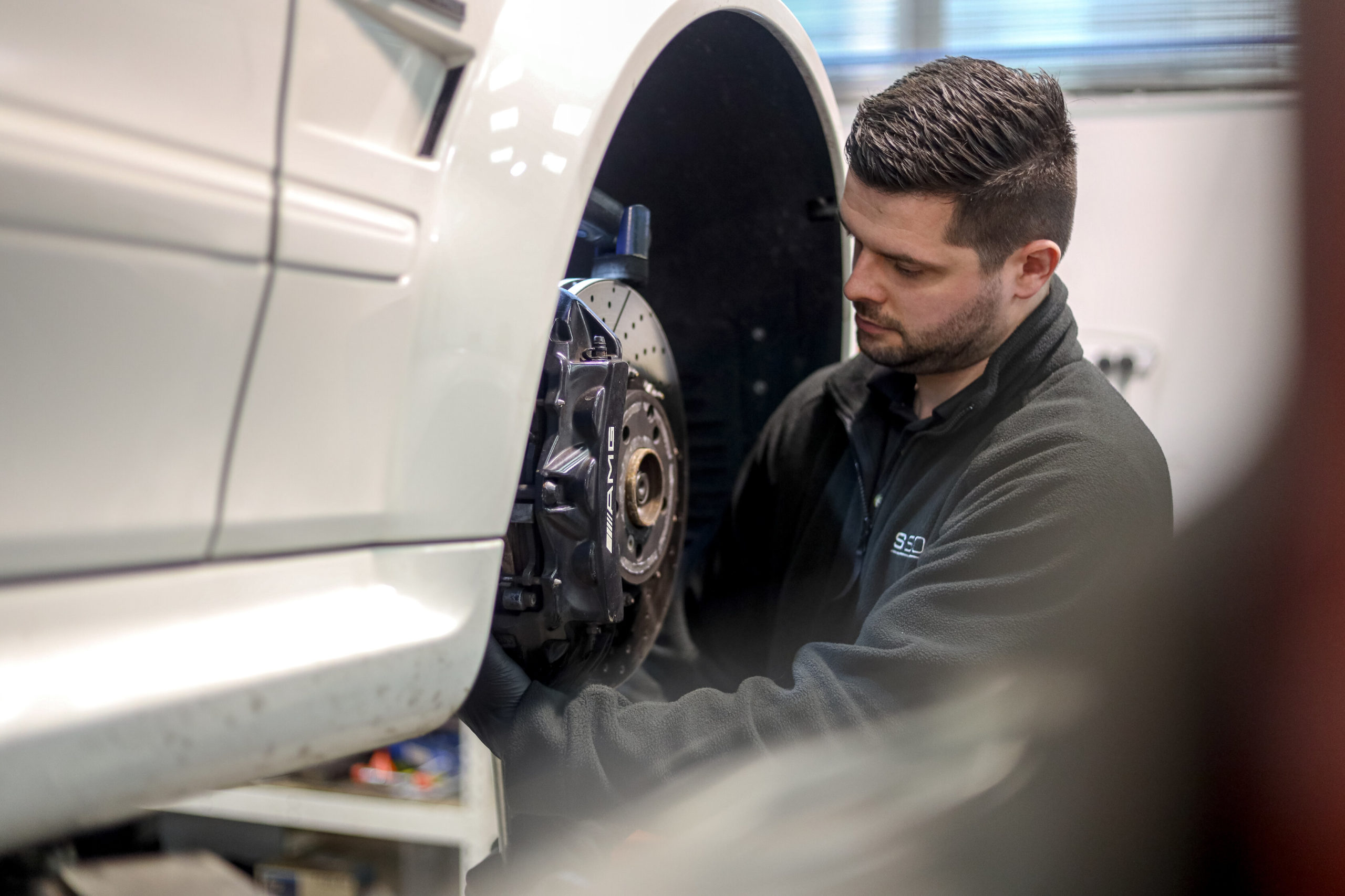 Mechanic removing wheel from R129 SL.